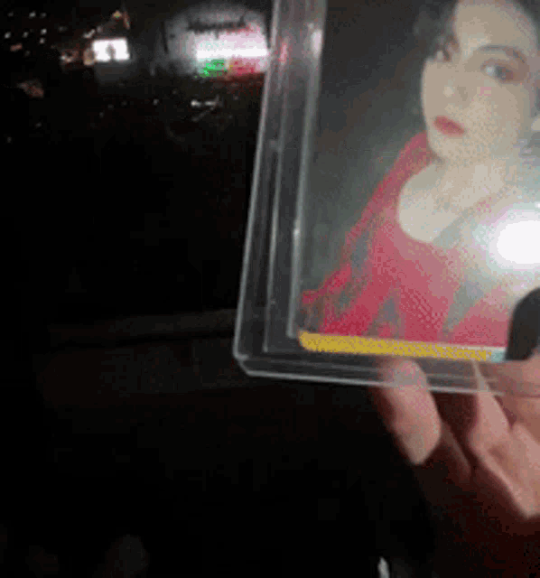 a person holding a picture of a woman in a red top