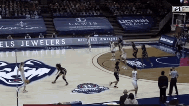 a basketball game is being played in a stadium with ads for lewis and michels jewelers