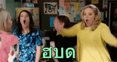 a group of women are standing in a room and one of them is wearing a yellow sweater that says ' a '