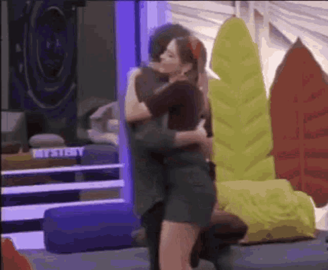 a man and a woman are hugging in a room with a sign that says ' a ' on it
