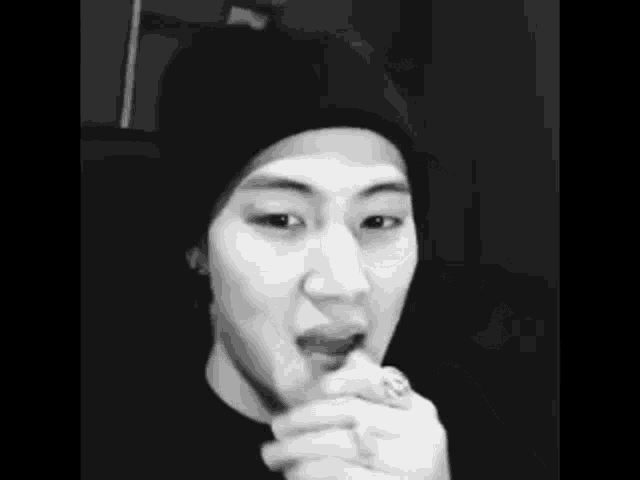 a black and white photo of a man wearing a beanie and a ring in his hand .