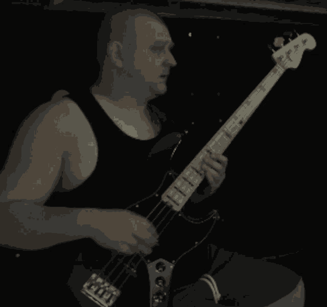 a man in a black tank top playing a guitar