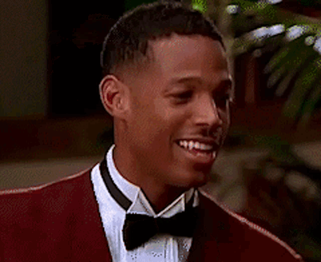 a man in a tuxedo is standing next to another man in a suit