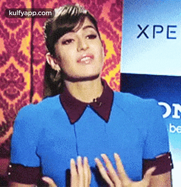 a woman in a blue shirt is standing in front of an advertisement for xperia
