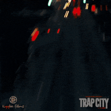 a man wearing glasses is talking on a phone with trap city written on the bottom right