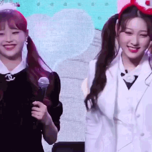 two girls are standing next to each other and one is holding a microphone