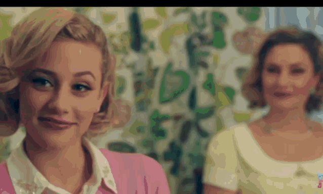 two women are standing next to each other and one is wearing a pink cardigan