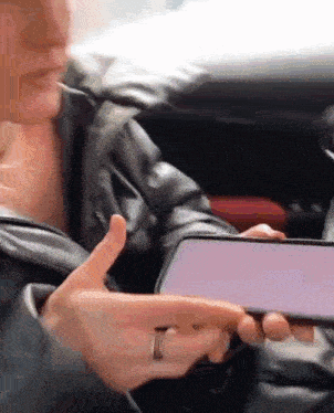 a person with a ring on their finger is holding a cell phone in their hand .
