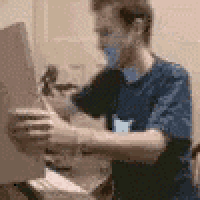 a man in a blue shirt is sitting at a table holding a piece of cardboard .