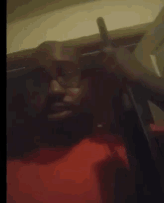 a man in a red shirt is sitting in a chair holding a stick .