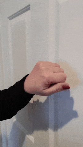 a woman 's hand with red nails is holding a white door