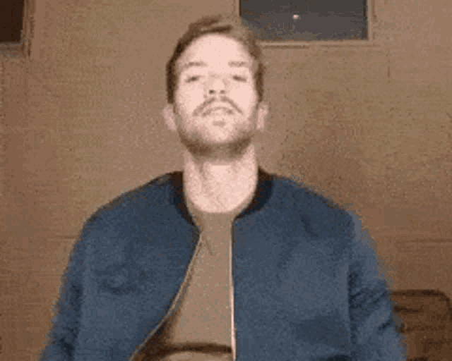 a man with a beard wearing a blue jacket and a green shirt .