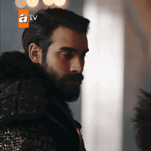 a man with a beard is standing in front of a sign that says atv