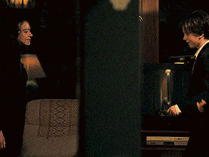 a man and a woman are standing in a dark room looking at each other