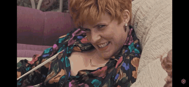 a woman in a floral shirt is smiling and holding a spoon