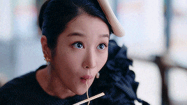 a woman is eating noodles with chopsticks .