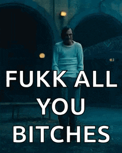 a man in a white shirt is standing in front of a building with the words " fuck all you bitches "