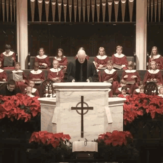 a man stands at a podium with a cross on it