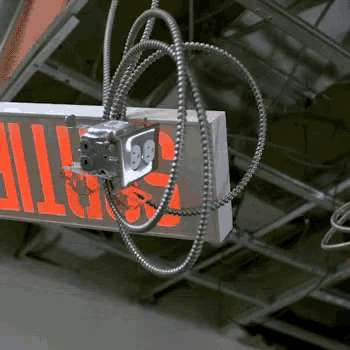 a red exit sign is hanging from the ceiling with a cord attached to it
