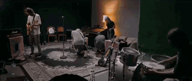 a group of people are playing instruments in a room with a green screen behind them .