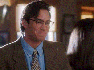 a man wearing glasses and a suit is smiling at a woman
