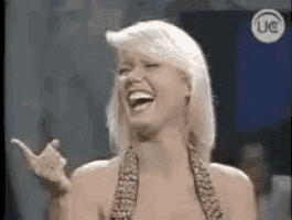a woman is laughing and pointing at the camera while wearing a bikini top .