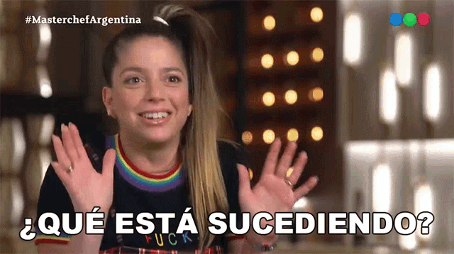 a woman in a rainbow shirt is smiling with the words que esta sucediendo written below her