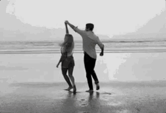 a man and a woman are dancing on a beach .