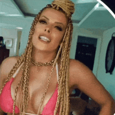a woman with blonde braids is wearing a pink bikini top and smiling .