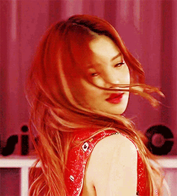 a woman with red hair looks over her shoulder at the camera