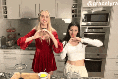 two women are making a heart with their hands in a kitchen