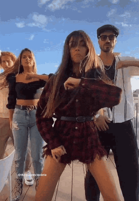 a woman in a plaid shirt is dancing with a man and two other women