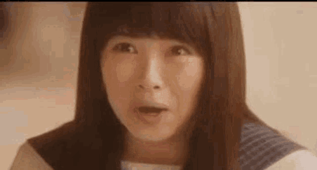 a woman with long hair is making a surprised face .