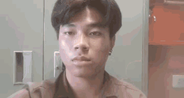 a young man is making a funny face while standing in front of a locker in a room .
