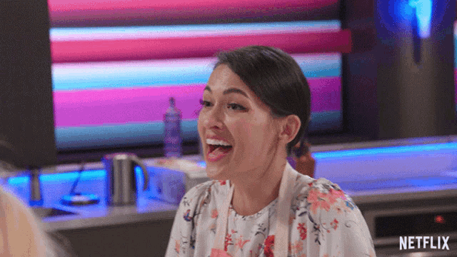 a woman is laughing in front of a netflix screen