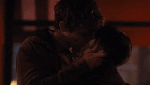 a man and woman kissing in a dark room