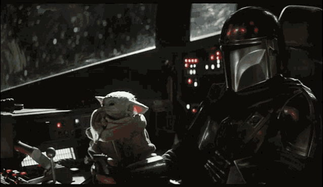a man in a helmet is holding a baby yoda