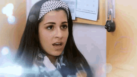 a woman in a headband is standing in front of a door with a padlock on it .