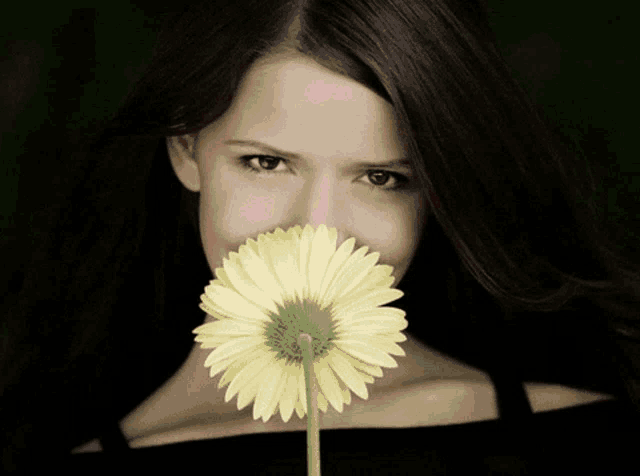 a woman is holding a flower in front of her face with a colorful greeting in a foreign language behind her
