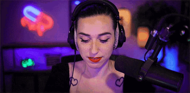 a woman wearing headphones is sitting in front of a microphone in a dark room .