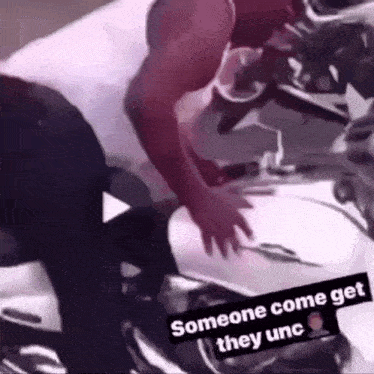 a man is standing next to a motorcycle with the words `` someone come get they unc '' written on the bottom .
