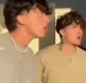 two young men are standing next to each other in a room .