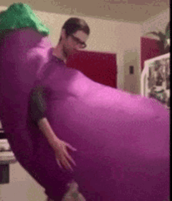 a man in a purple eggplant costume is standing next to a refrigerator .