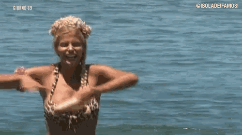 a woman in a bikini is standing in the water holding a stick .