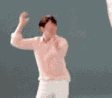 a man in a pink shirt is dancing with his arms outstretched .