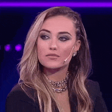 a woman wearing a choker and earrings is looking at the camera .