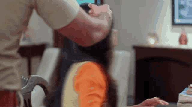 a man is holding a woman 's head while she sits on a chair