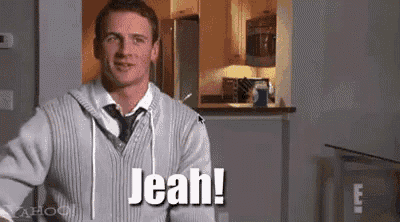 a man wearing a sweater and tie is standing in a kitchen and says jeah !