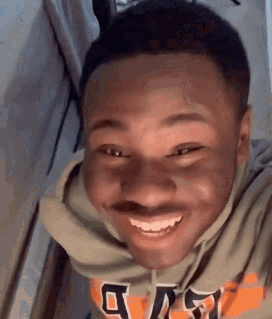 a young man with a mustache and a hoodie is smiling .
