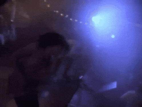 a person is dancing in a dark room with blue lights